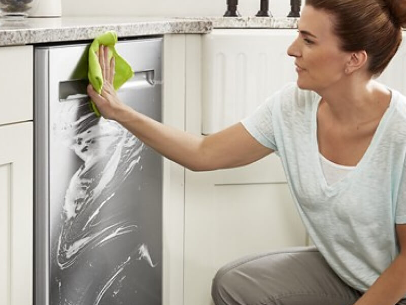 Person cleaning the exterior of a dishwasher Person cleaning the exterior of a dishwasher