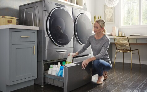 A woman putting away cleaning supplies in a laundry pedestal