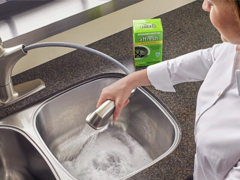 A person cleaning their sink disposal with affresh® garbage disposal cleaner tablets