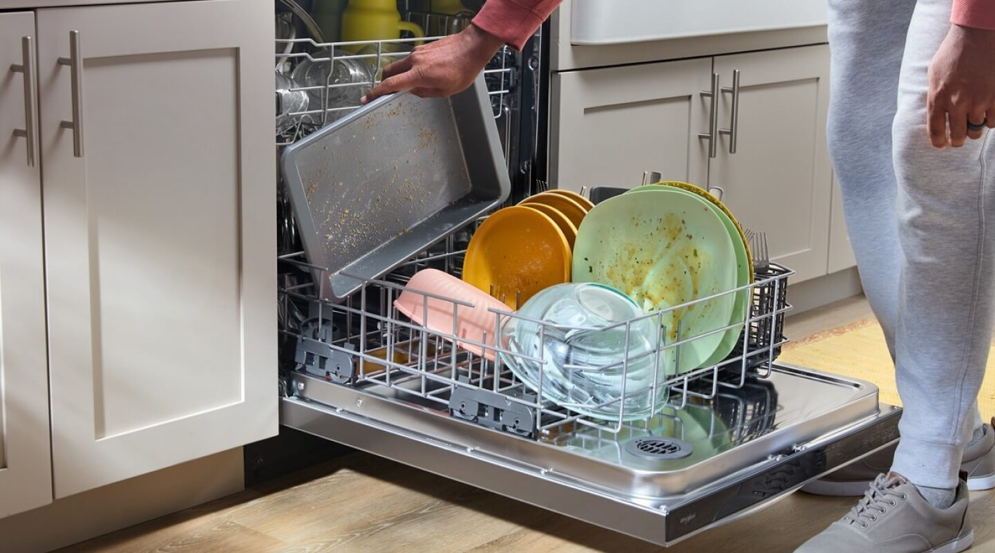 A person loading dishes into a dishwasher