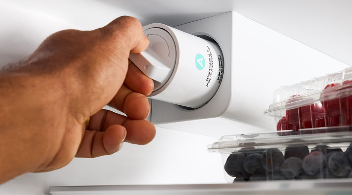 A person changing a fridge filter