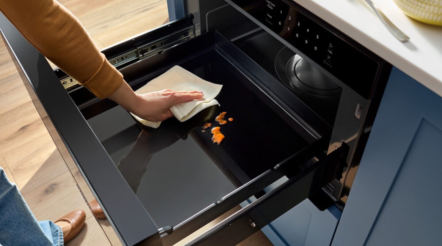 A person cleaning a Whirlpool® Microwave Drawer