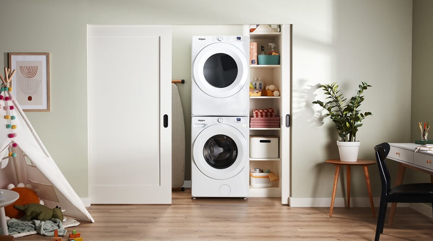 White stackable front load washer and dryer inside a laundry closet