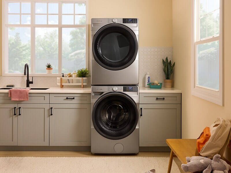 Stainless steel front load washer and dryer in a laundry room with gray cabinetry Stainless steel front load washer and dryer in a laundry room with gray cabinetry