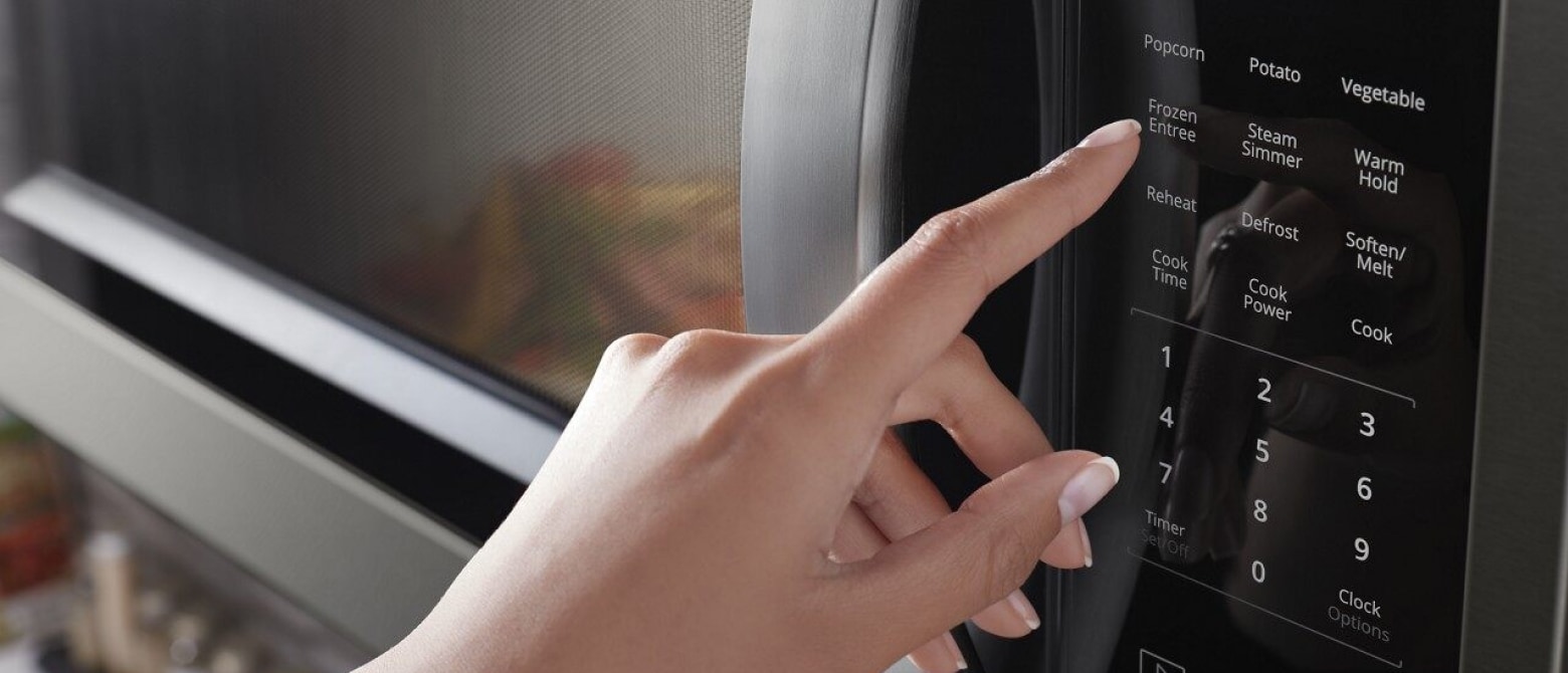 Hand touching microwave control panel