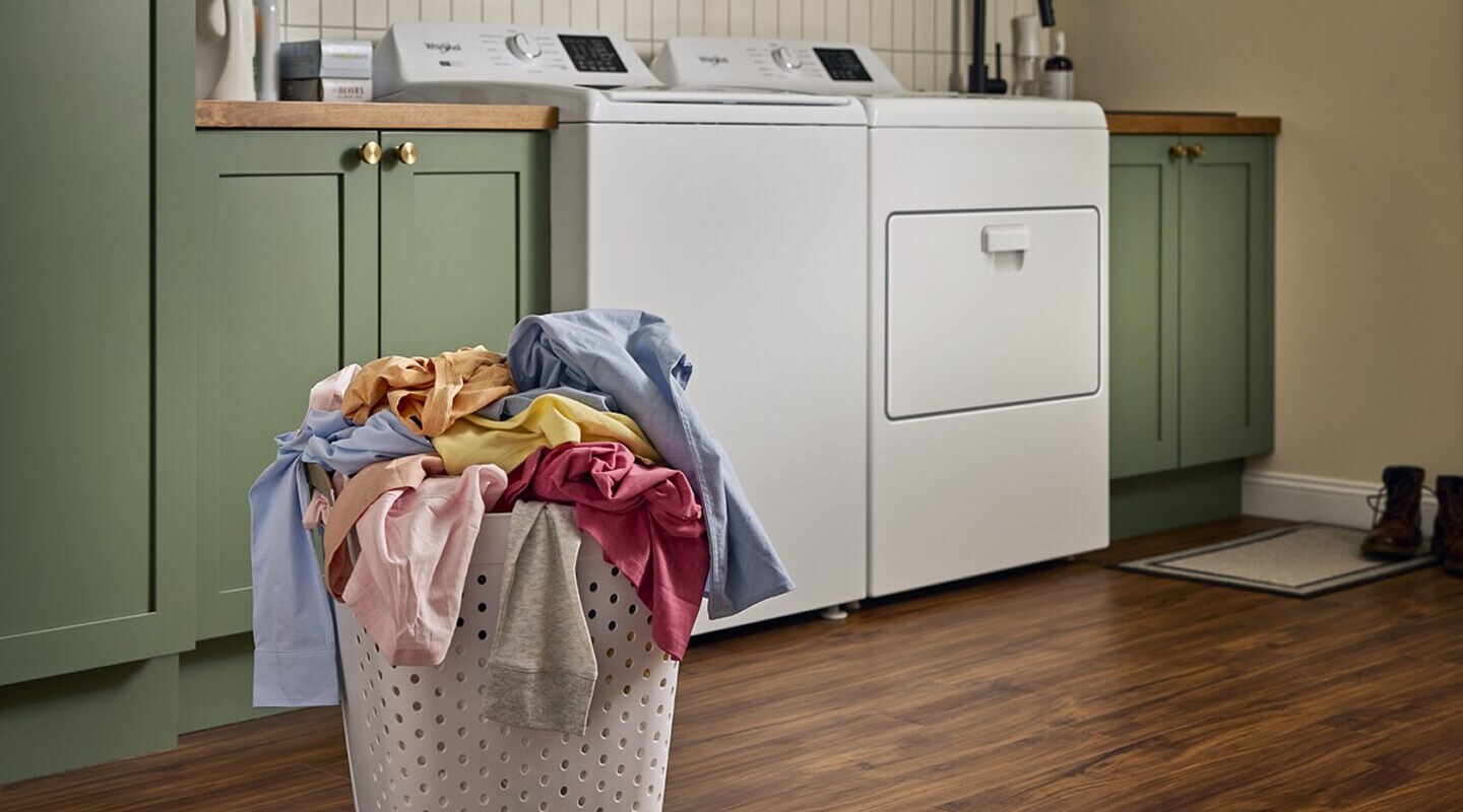 A basket of laundry in front of a washer and dryer set in a laundry room A basket of laundry in front of a washer and dryer set in a laundry room