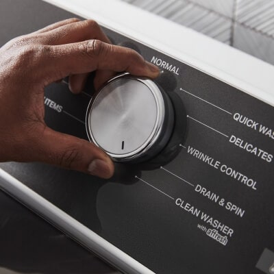 Close up of a person selecting a washer setting on the control panel of a Whirlpool® Washer