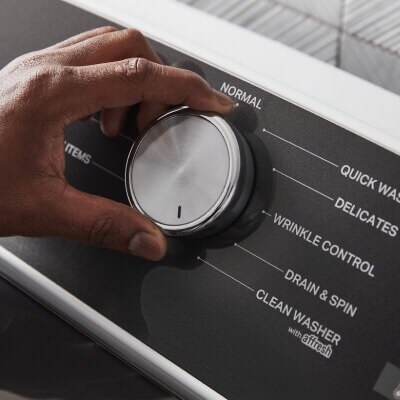 Close up of a person selecting a washer setting on the control panel of a Whirlpool® Washer