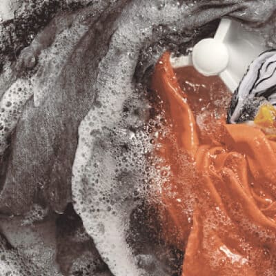 Interior of a Whirlpool® Washer with an impeller washing orange, gray and white garments