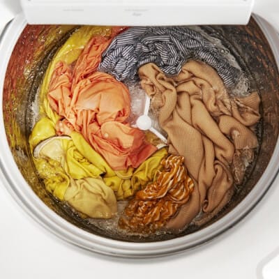 Interior of a Whirlpool® Washer with an impeller washing yellow, orange, gray and brown garments