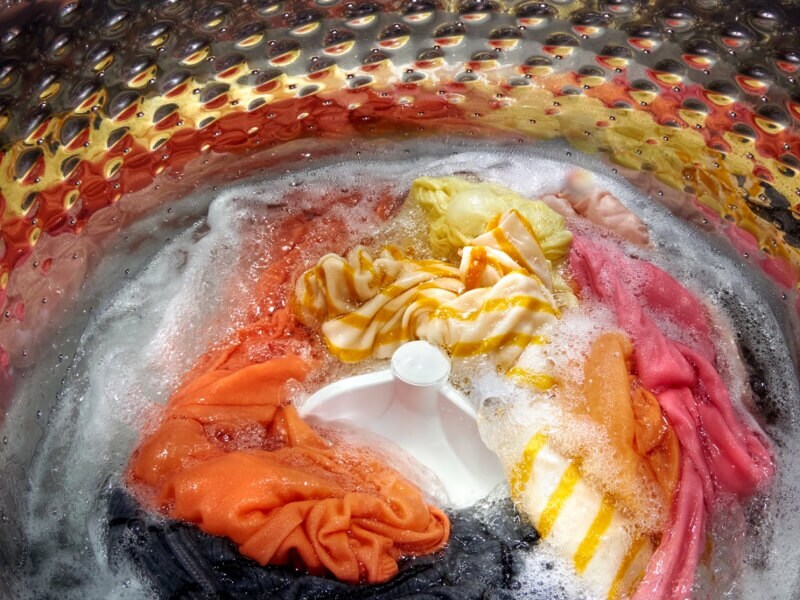 Interior of a Whirlpool® Washer with an impeller washing yellow, orange, pink, gray and white garments Interior of a Whirlpool® Washer with an impeller washing yellow, orange, pink, gray and white garments