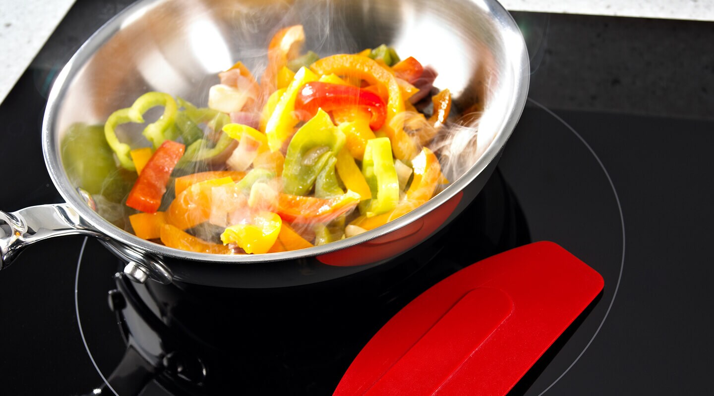 Bell peppers cooking in a pan on an electric cooktop Bell peppers cooking in a pan on an electric cooktop
