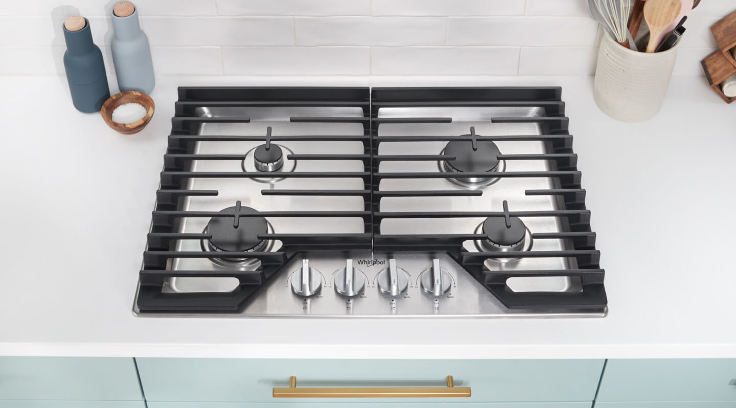A four-burner gas cooktop built into white counters