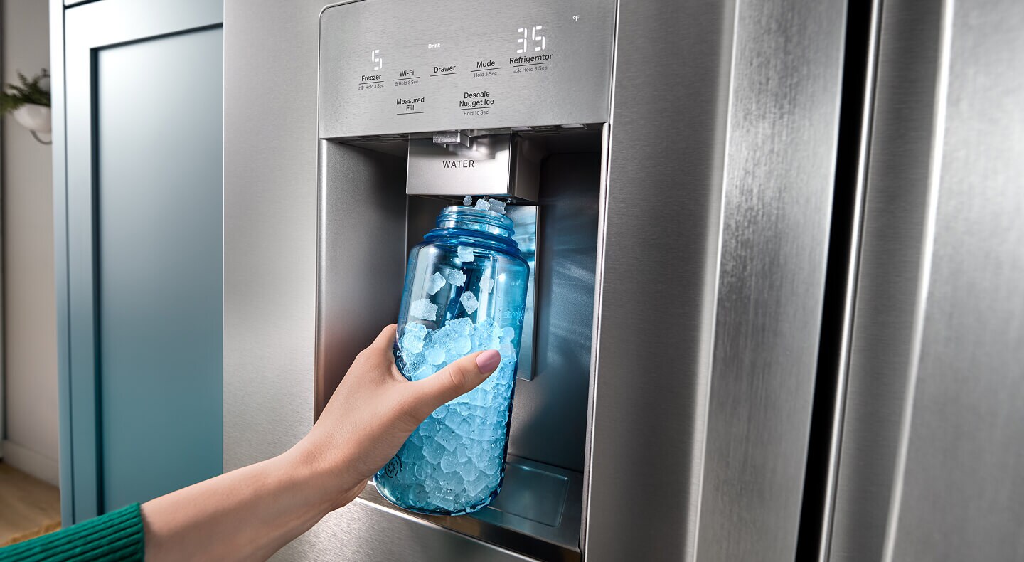 A person dispensing nugget ice cubes into a translucent blue bottle