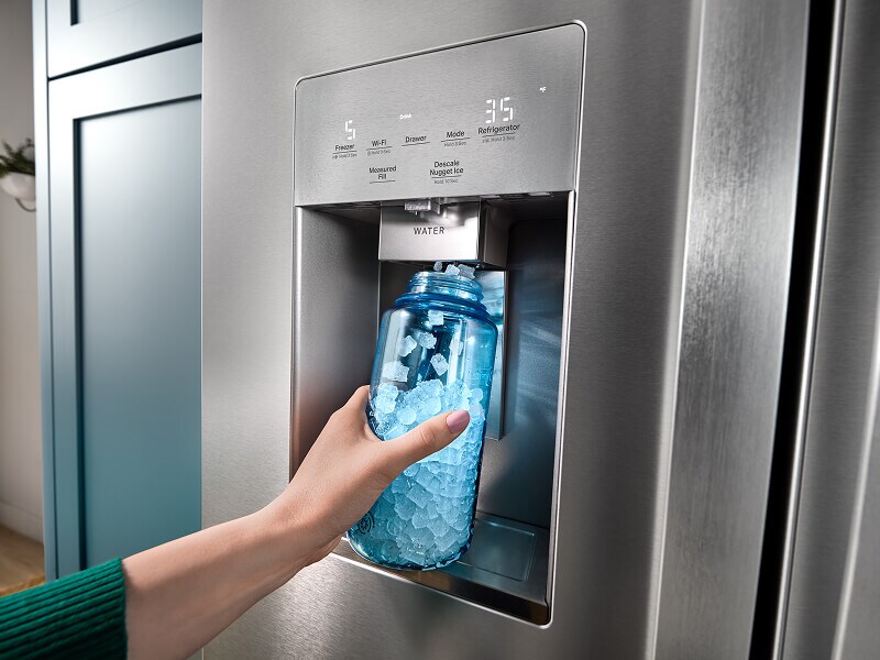 A person dispensing nugget ice cubes into a translucent blue bottle