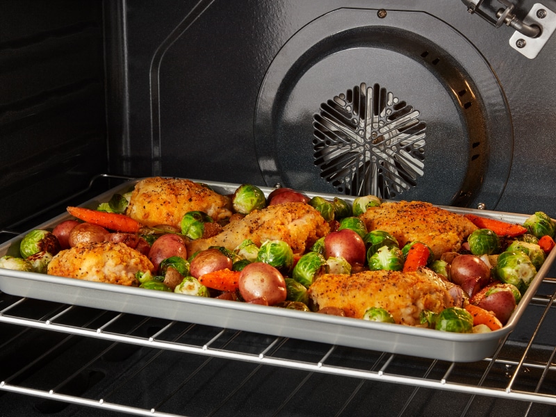 Chicken and vegetables roasting in a convection oven Chicken and vegetables roasting in a convection oven