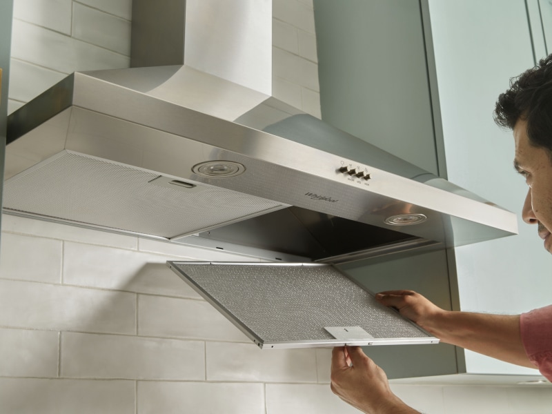 A person changing the filter on a range hood. A person changing the filter on a range hood.