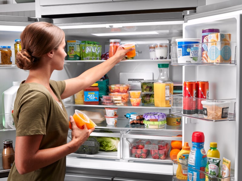Person placing items on top shelf of Whirlpool® refrigerator Person placing items on top shelf of Whirlpool® refrigerator
