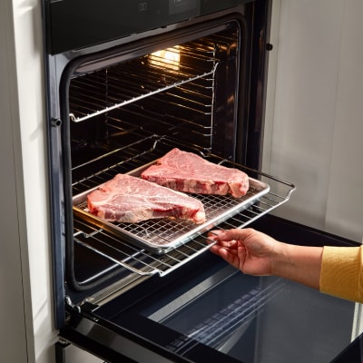 A person baking meat in the oven