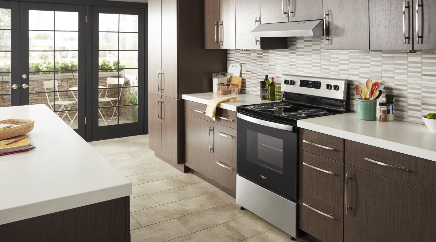 The interior of a kitchen with an electric range and under cabinet range hood