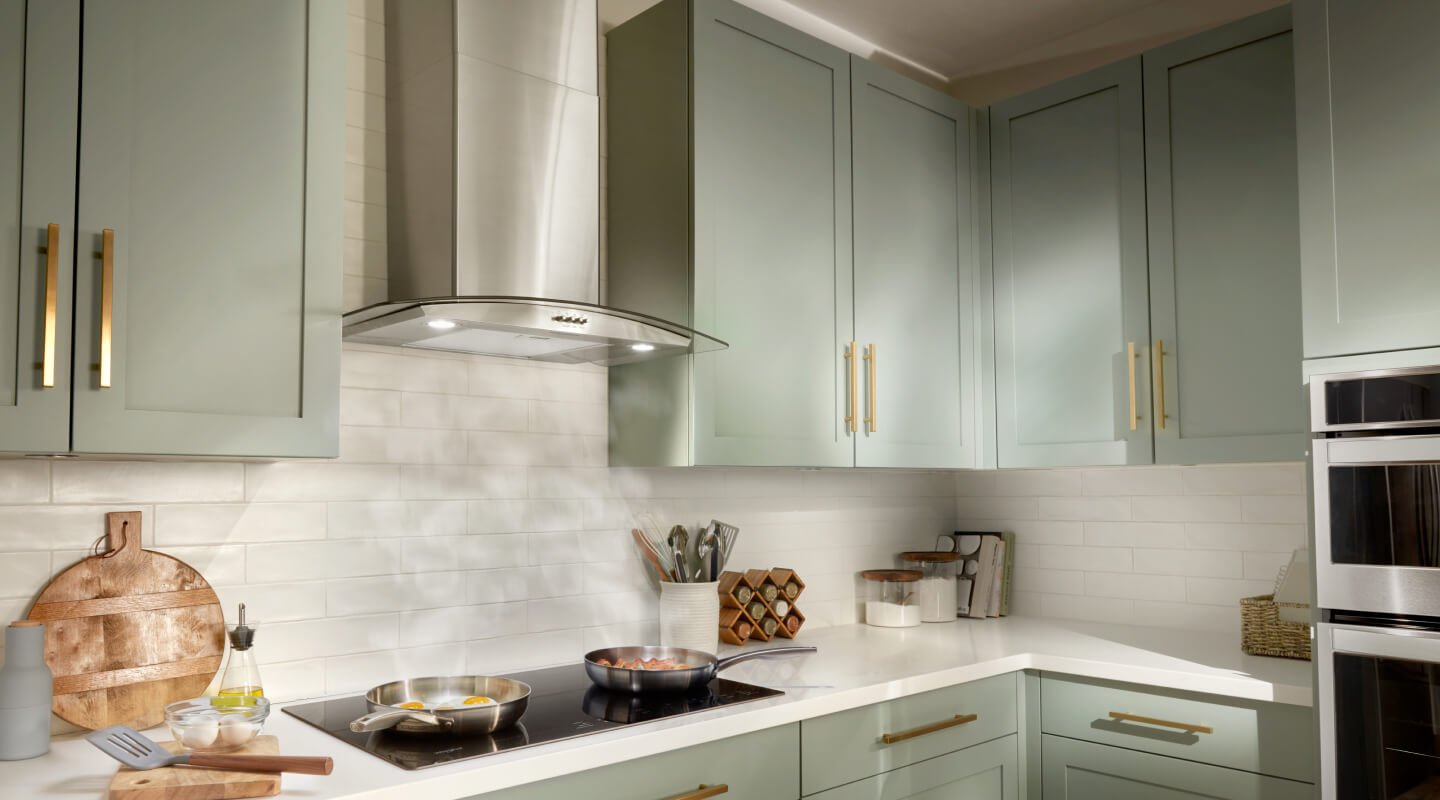 A Whirlpool® Chimney Wall Mount Range Hood and Range in a kitchen