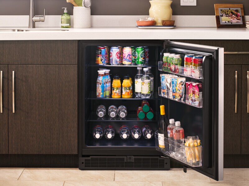 Fully stocked open undercounter refrigerator in a kitchen  Fully stocked open undercounter refrigerator in a kitchen