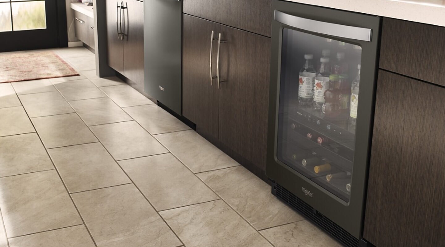 An undercounter beverage center surrounded by dark cabinetry