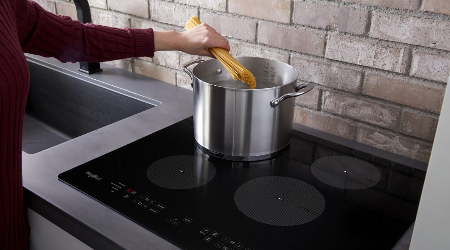 Person adding pasta to a pot of water