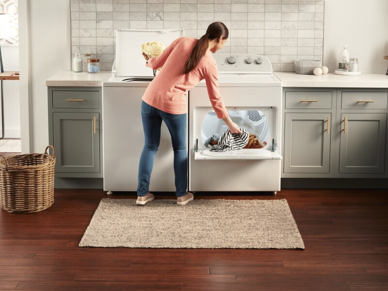 A person removing laundry from a Whirlpool® Top Load Washer and putting items into a Whirlpool® Dryer A person removing laundry from a Whirlpool® Top Load Washer and putting items into a Whirlpool® Dryer