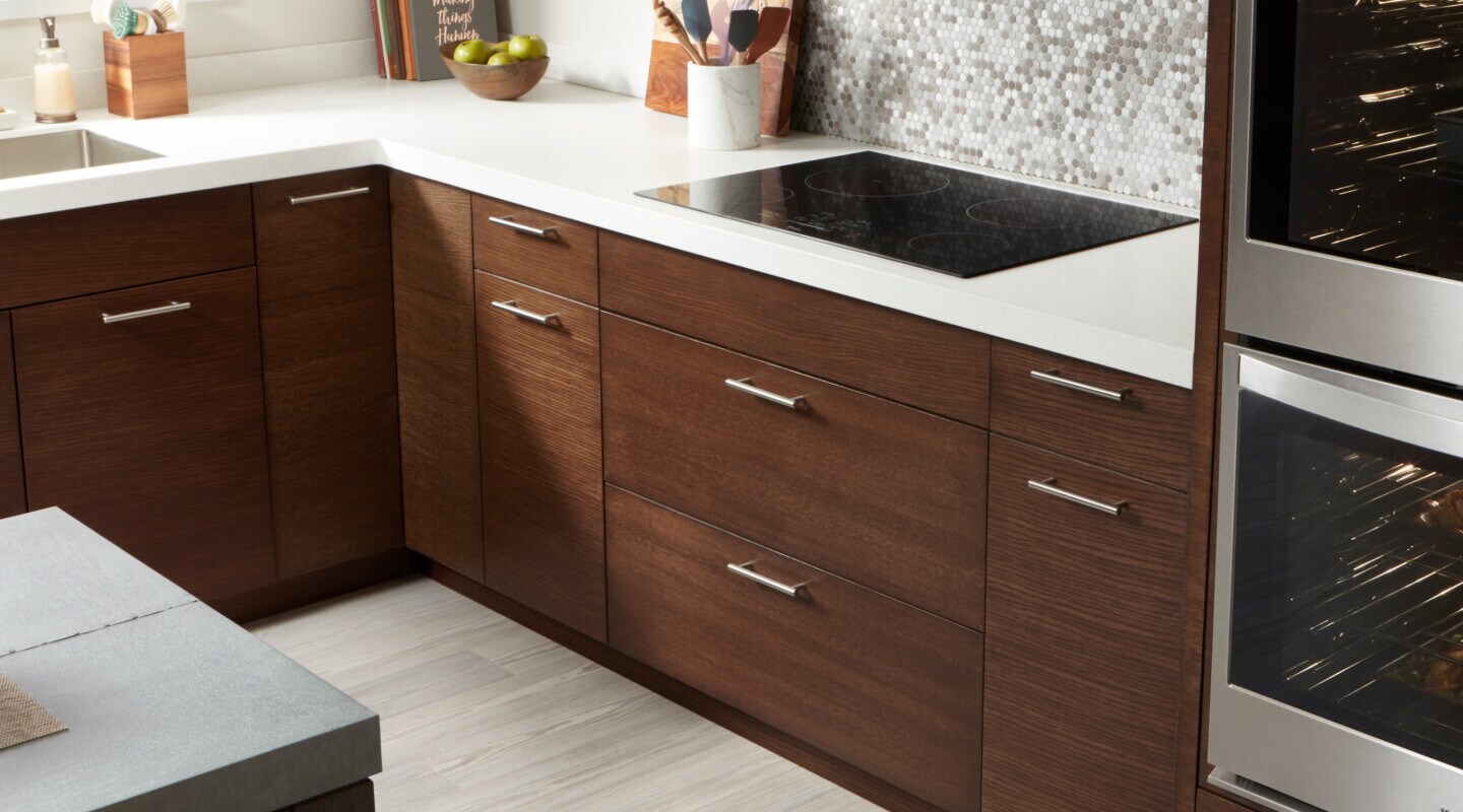 Whirlpool® electric cooktop and dark wooden cabinetry with white countertops Whirlpool® electric cooktop and dark wooden cabinetry with white countertops
