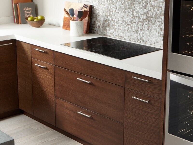 Whirlpool® electric cooktop and dark wooden cabinetry with white countertops Whirlpool® electric cooktop and dark wooden cabinetry with white countertops
