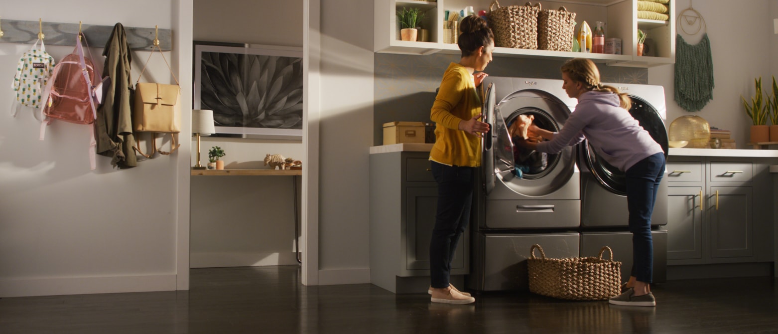 Two women unload laundry from a front load washer