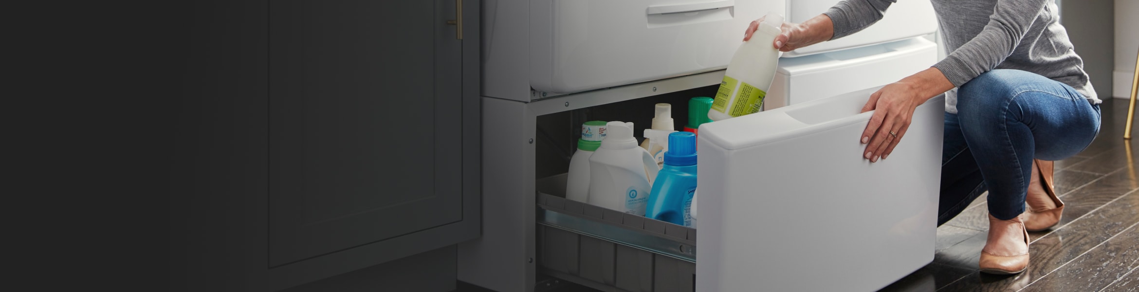A woman placing laundry detergent in a washer pedestal