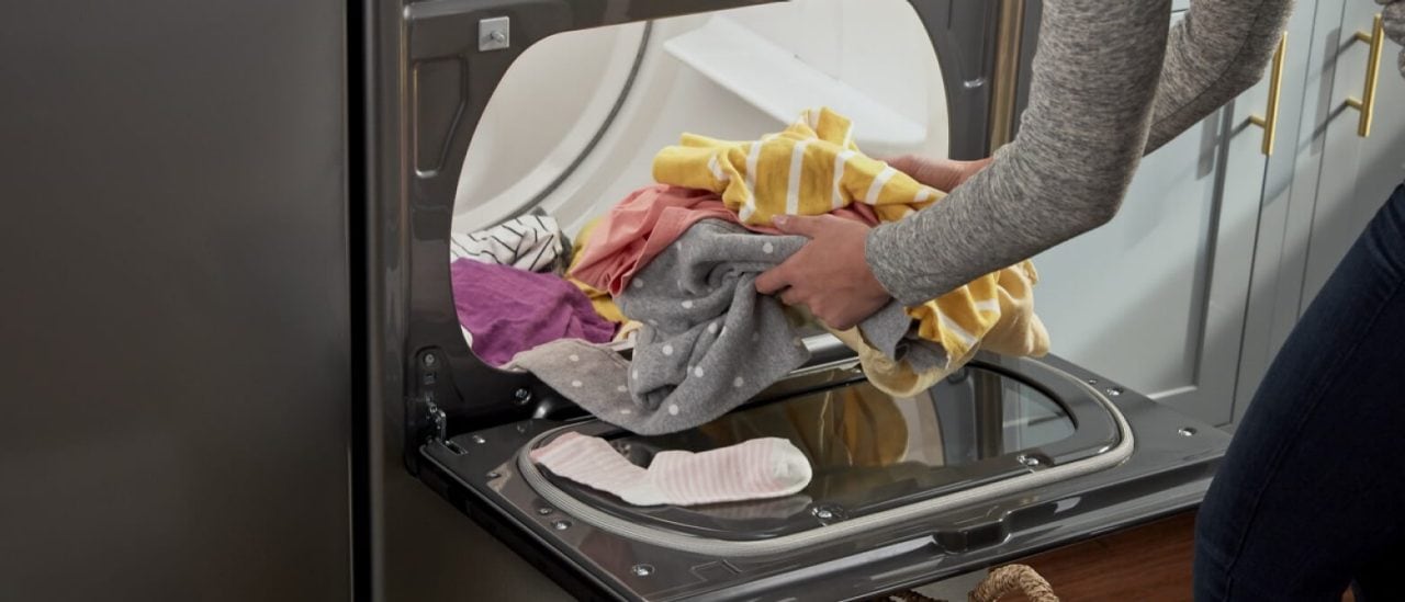 A person removing clothes from a dryer A person removing clothes from a dryer