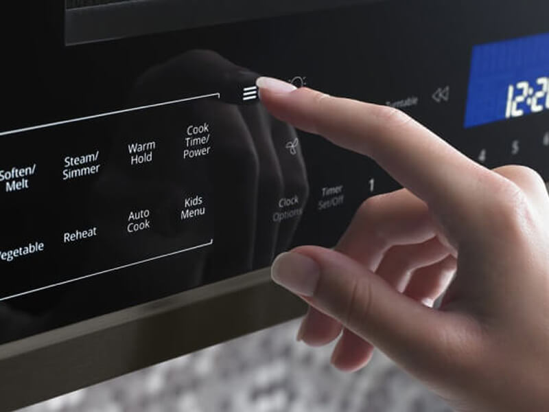 Hand pressing buttons on microwave control panel Hand pressing buttons on microwave control panel