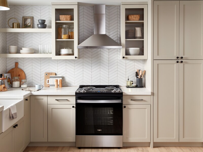 A stainless steel range hood above a black range A stainless steel range hood above a black range