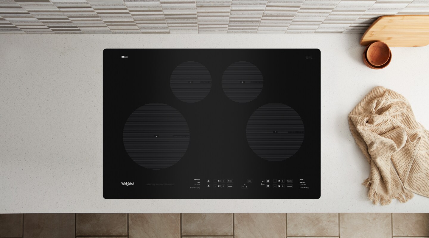 A black Whirlpool® cooktop next to various kitchen items A black Whirlpool® cooktop next to various kitchen items