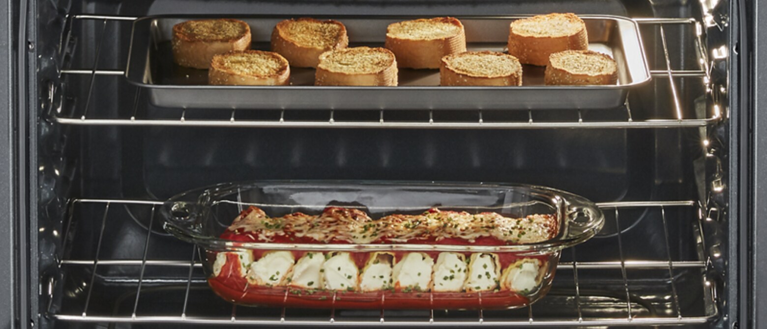 Garlic bread and manicotti inside an oven Garlic bread and manicotti inside an oven