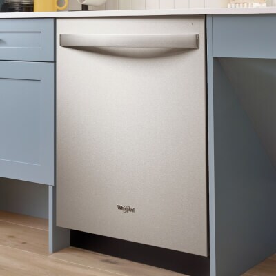 A Whirlpool® Built-In Dishwasher with Top Control and a towel handle between powder blue cabinets
