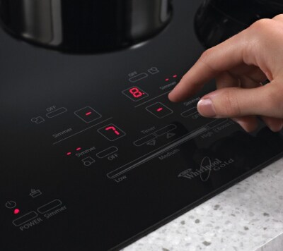 A hand choosing settings on a Whirlpool® Induction Cooktop