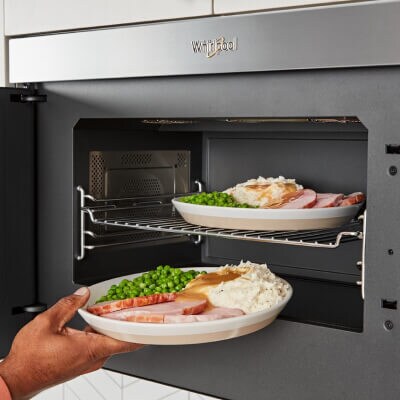 A person adjusting food in a microwave