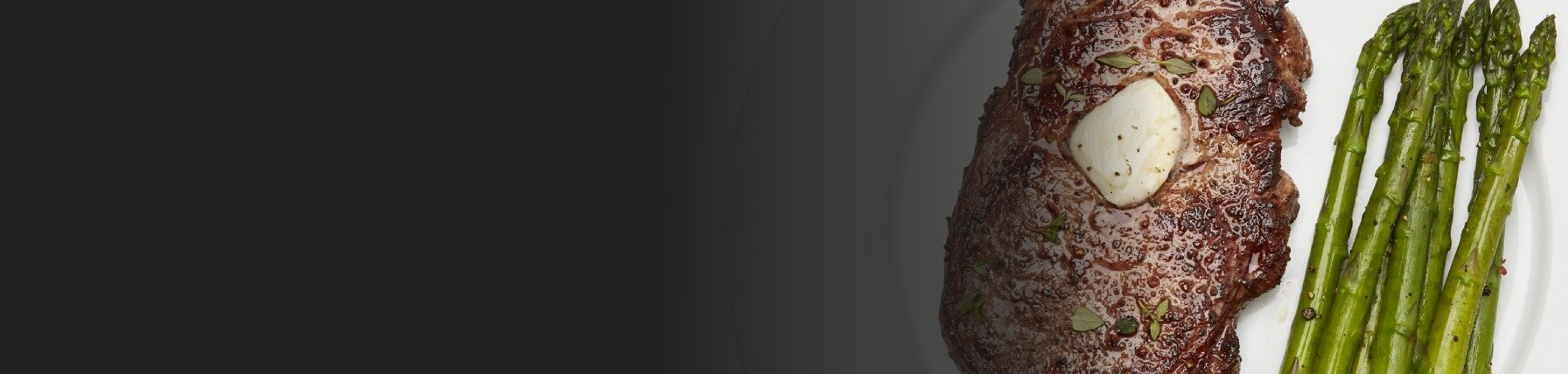 A butter garnished steak dish with asparagus on the side