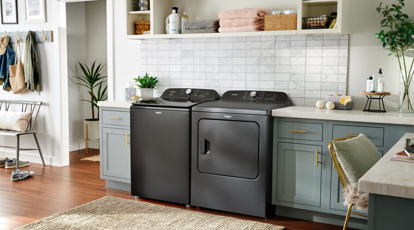 Black washer and dryer next to green cabinets