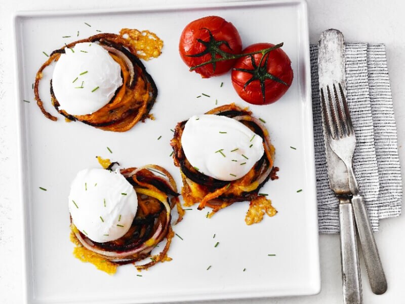 Poached eggs on a white plate with some tomatoes on the side
