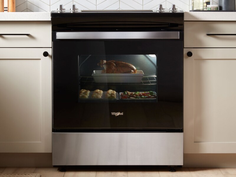 A black slide-in range with various dishes baking inside