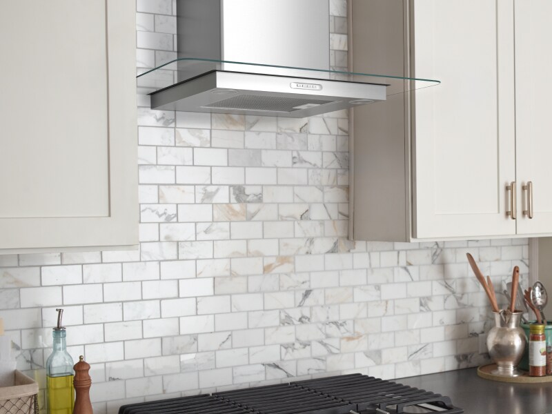 Stainless steel range hood between white cabinetry Stainless steel range hood between white cabinetry