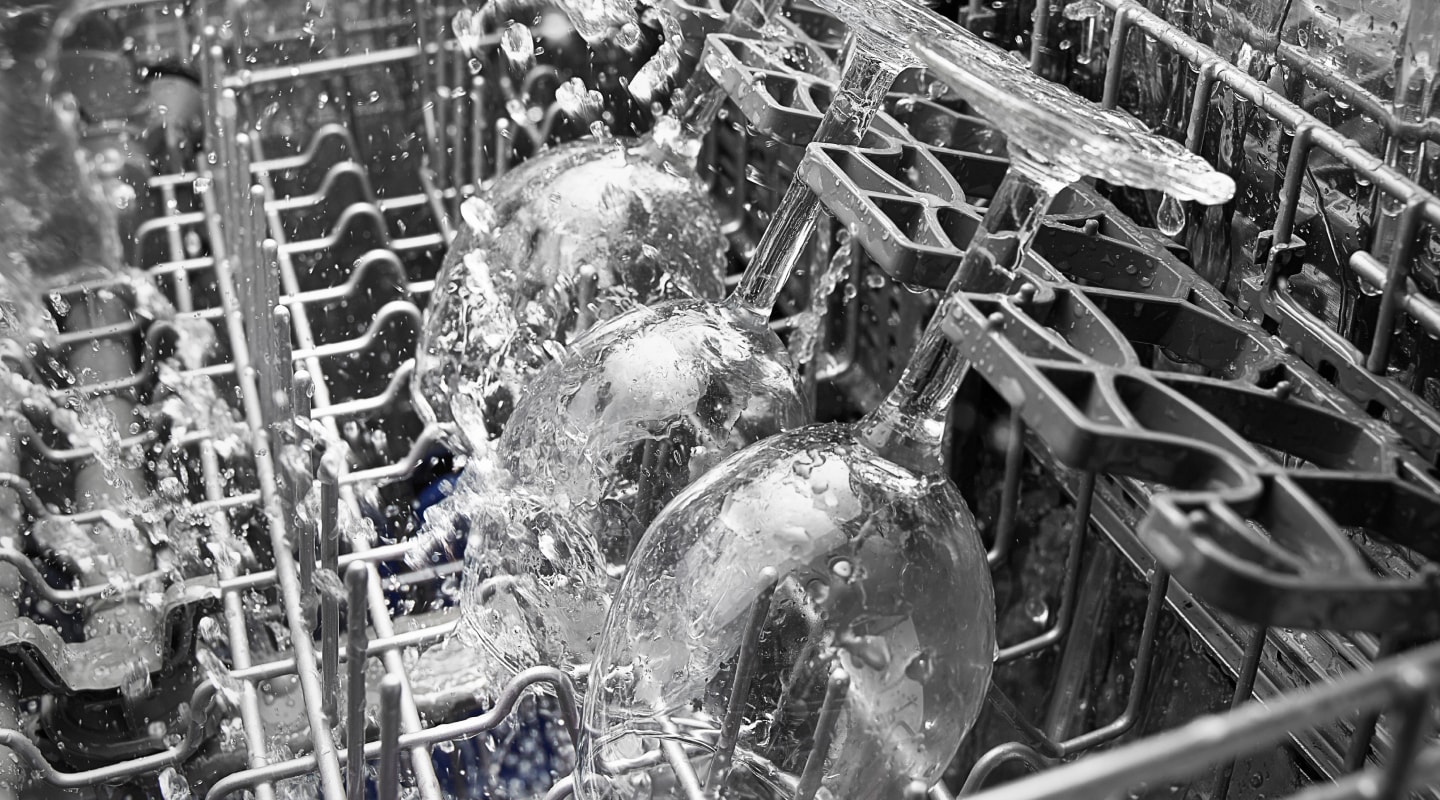Wine glasses being sprayed in a dishwasher Wine glasses being sprayed in a dishwasher