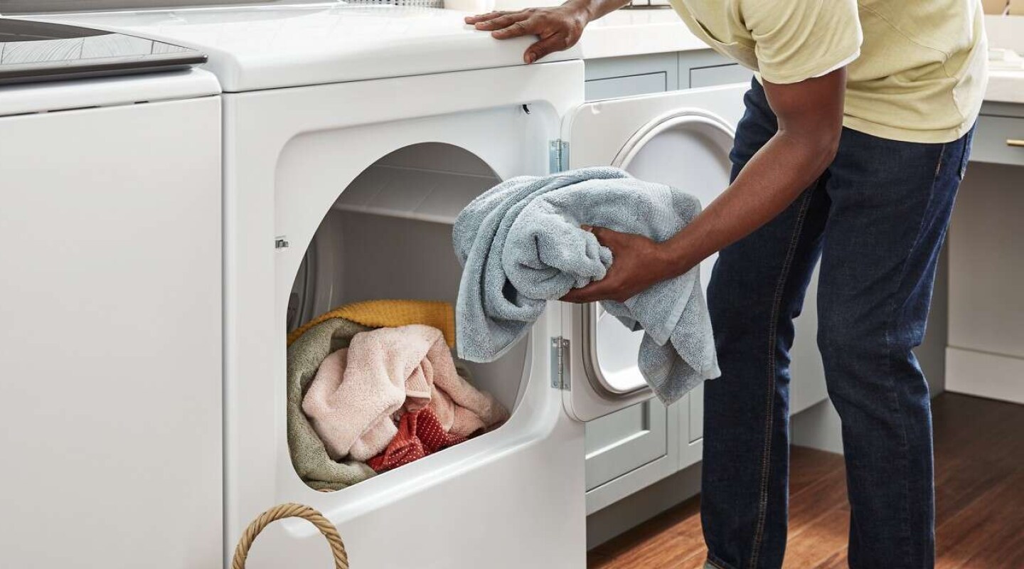 Person removing a towel from a Whirlpool brand dryer Person removing a towel from a Whirlpool brand dryer