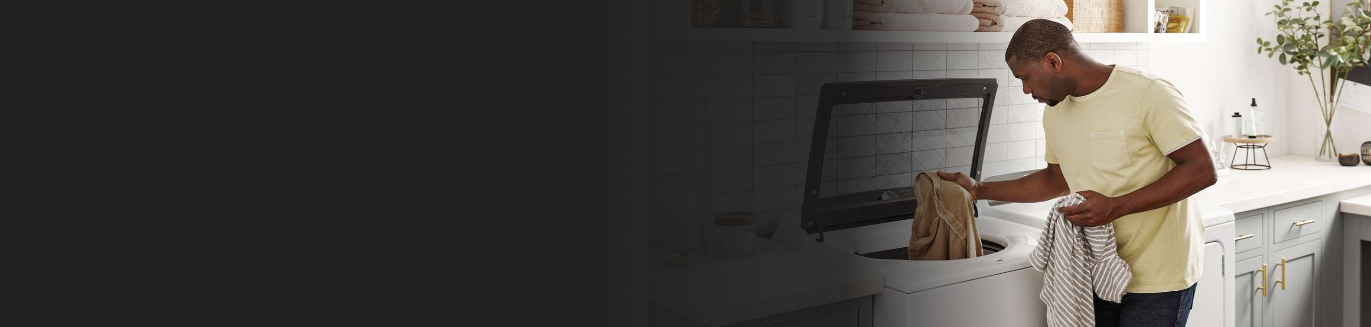 Person loading clothes into a white top load washer