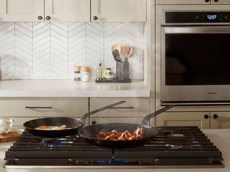 Pans cooking food on a Whirlpool® cooktop Pans cooking food on a Whirlpool® cooktop